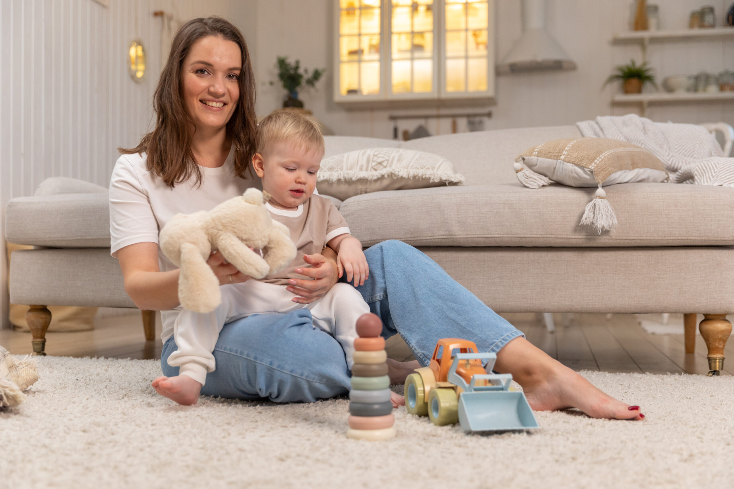 Happy family at home. Mother and baby boy playing with toys at home indoors. Little toddler child and babysitter nanny having fun together. Young woman mom kid son rest in living room